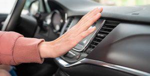Person holding hand out in front of the car air conditioning