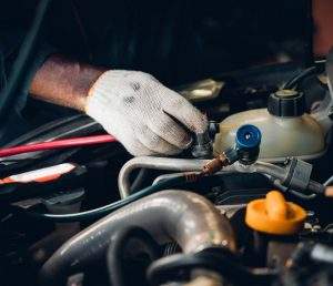 Mechanics hand reaching towards cars' air con pipes